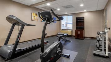 A gym with treadmills, an elliptical, a bench, and a weight rack.