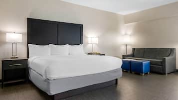 Una habitación de hotel con una cama grande, mesitas de noche, una silla y un escritorio.