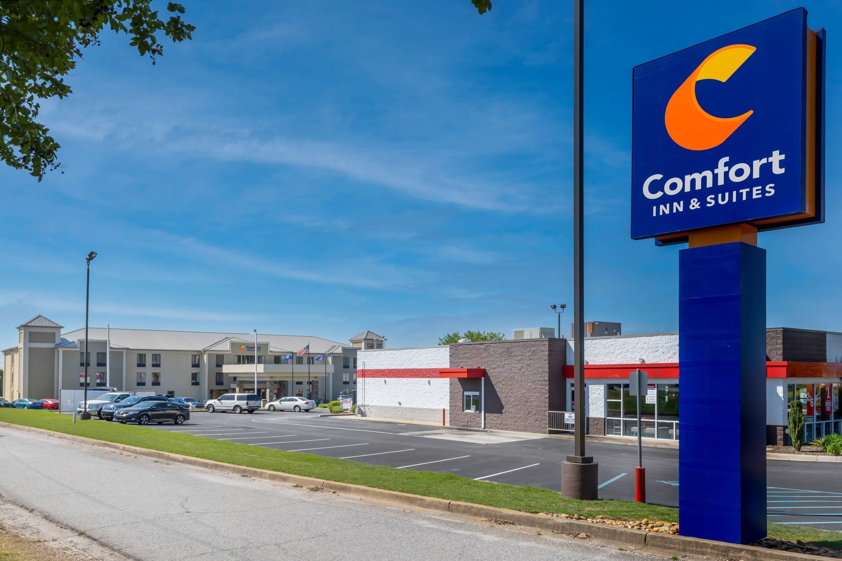 A Comfort Inn & Suites with a clear blue sky, parking lot, and a building with a red roof.