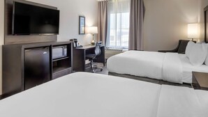 A hotel room with a flat-screen TV, a desk with a chair, two beds, a window with curtains, and an air conditioning unit.