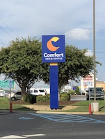 Señal de Comfort Inn & Suites con fondo azul y un logotipo en forma de media luna naranja.