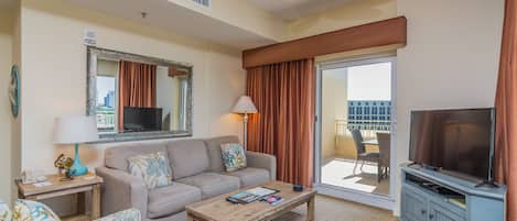 Un salon comprenant un canapé, une table basse, un téléviseur et un balcon avec vue.