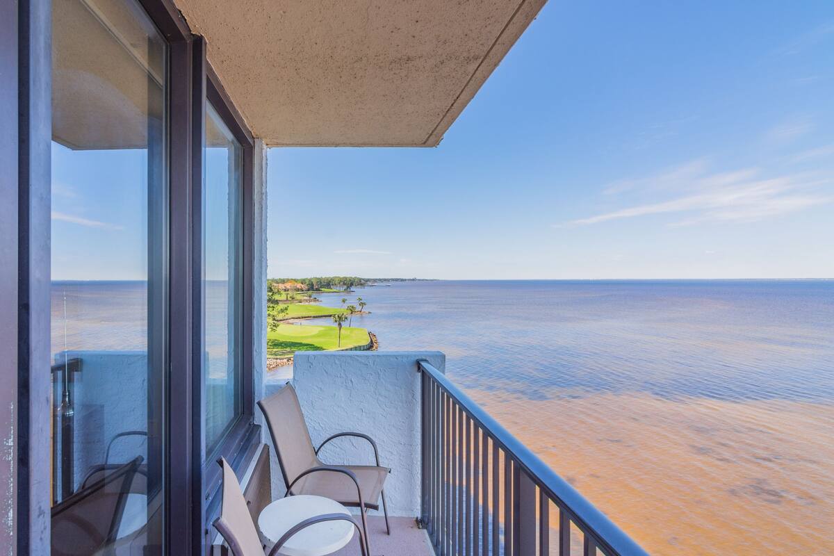A balcony with a view of a calm body of water and a distant shoreline.