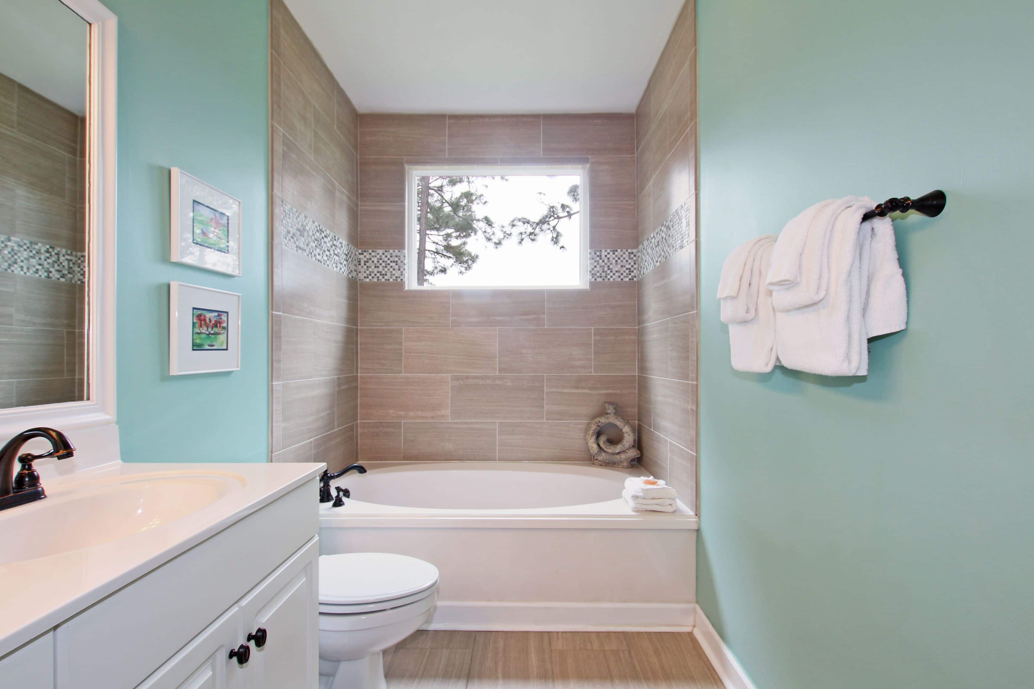 A bathroom with a bathtub, toilet, sink, and a window.