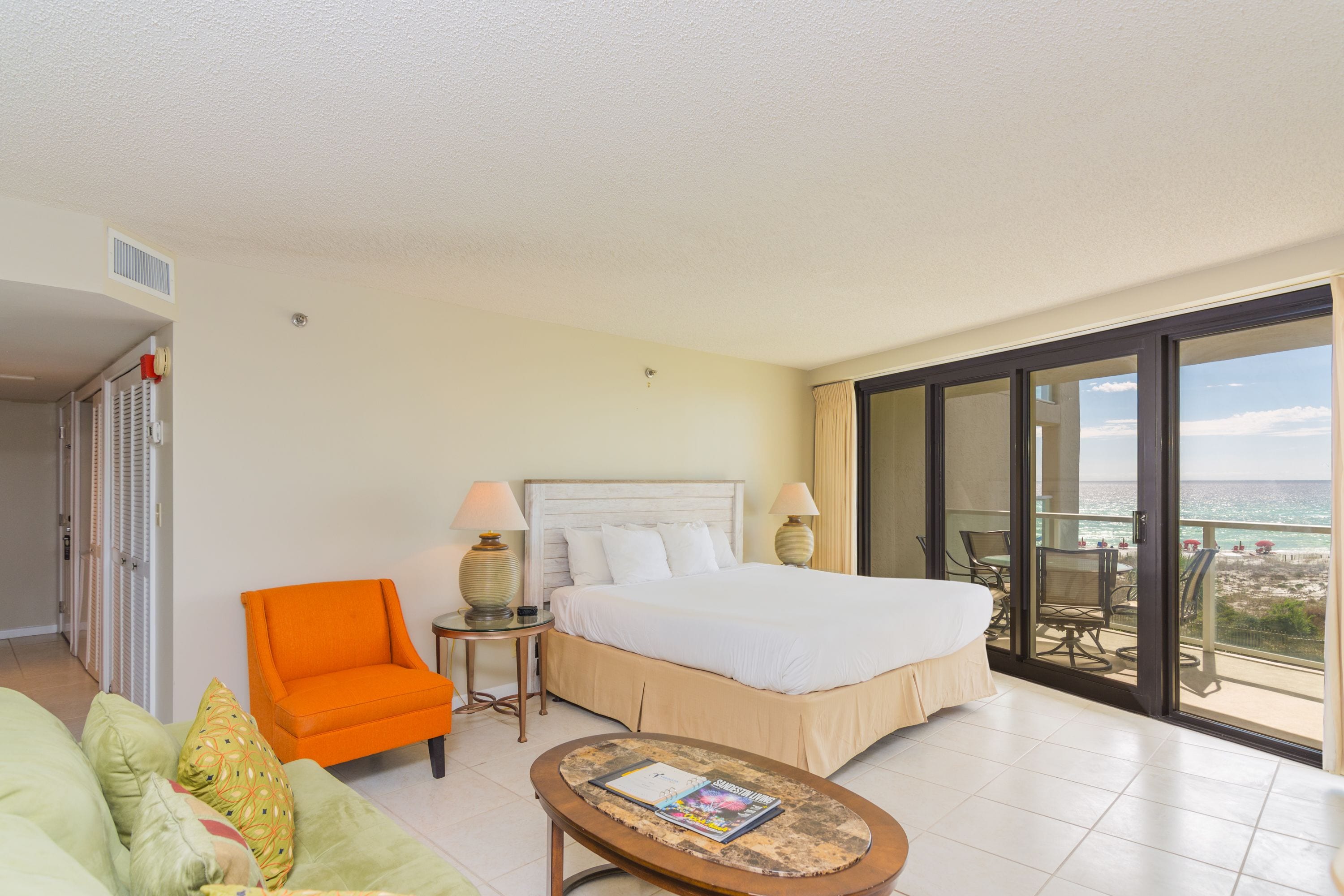 A hotel room with a bed, a chair, a table, and a balcony with a view.