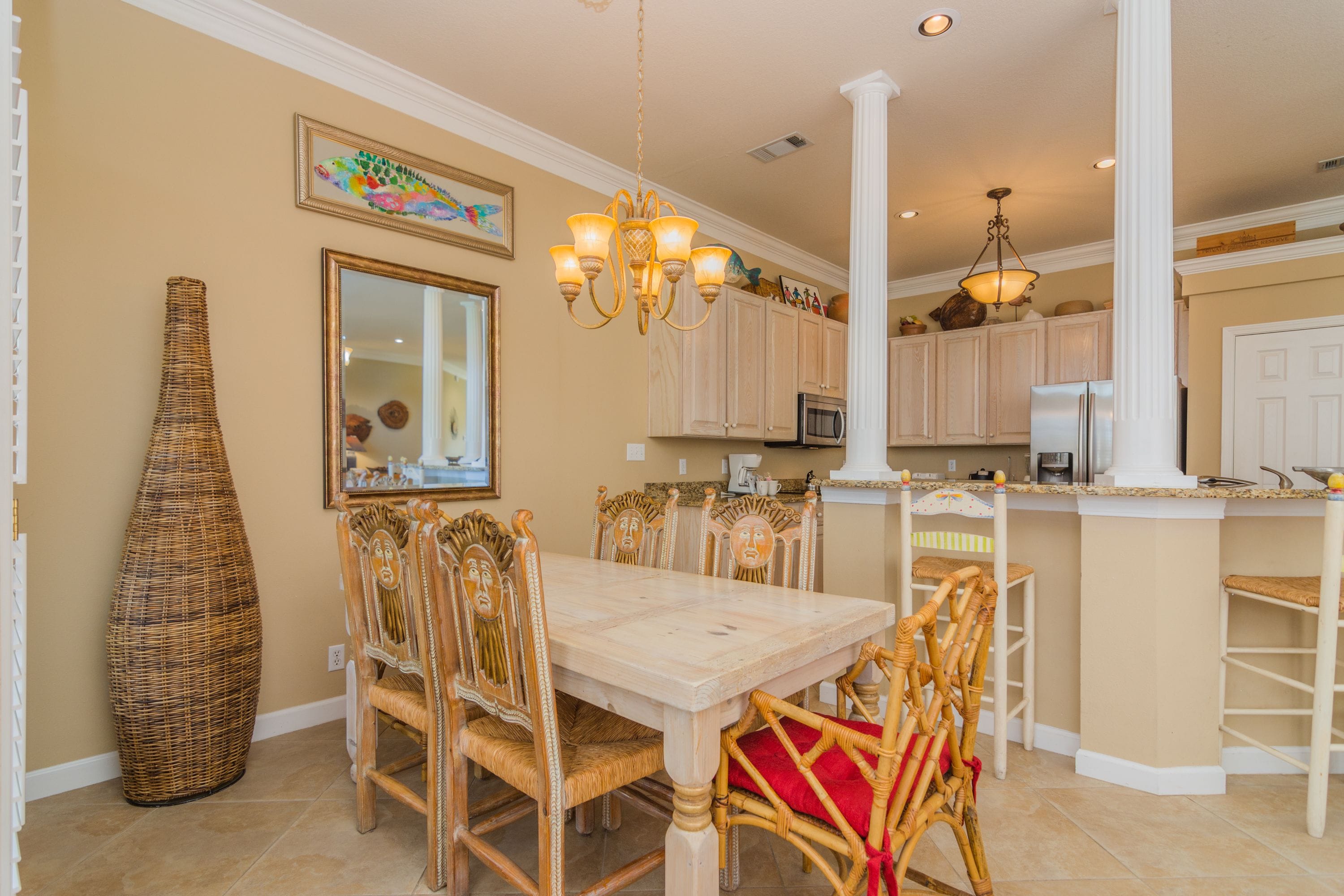 A dining area with a large table, wicker chairs, and a tall vase.