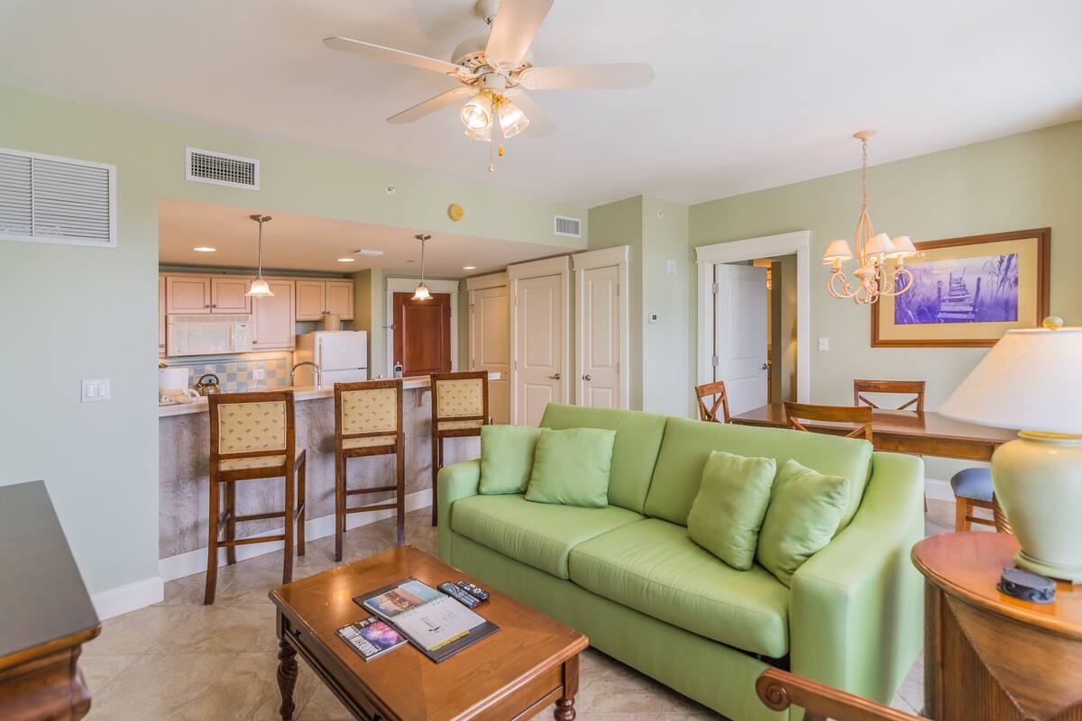 A living room with a green sofa, wooden coffee table, and a ceiling fan.