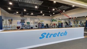 Un gimnasio con una pared que dice 'Estiramientos' y diverso equipo de ejercicio.
