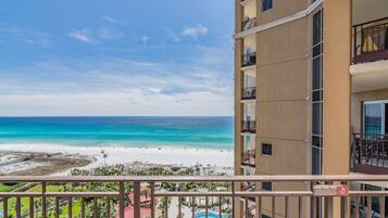 A high-rise hotel with balconies overlooking a beach and a pool area.