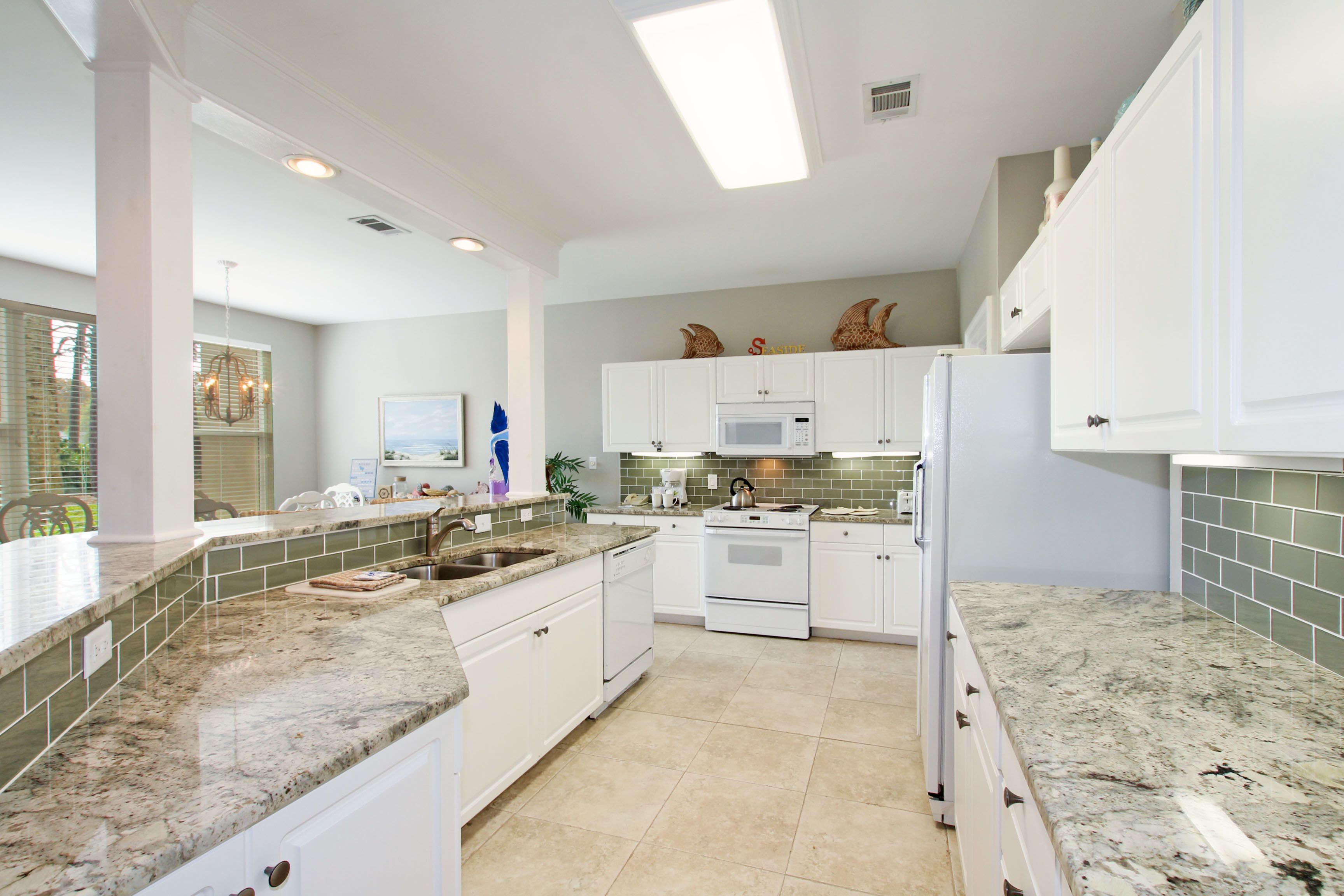 A modern kitchen with white cabinets, a granite countertop, a microwave, and a stove.