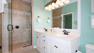 A modern bathroom with a glass shower enclosure, a white vanity with a large mirror, and a toilet.