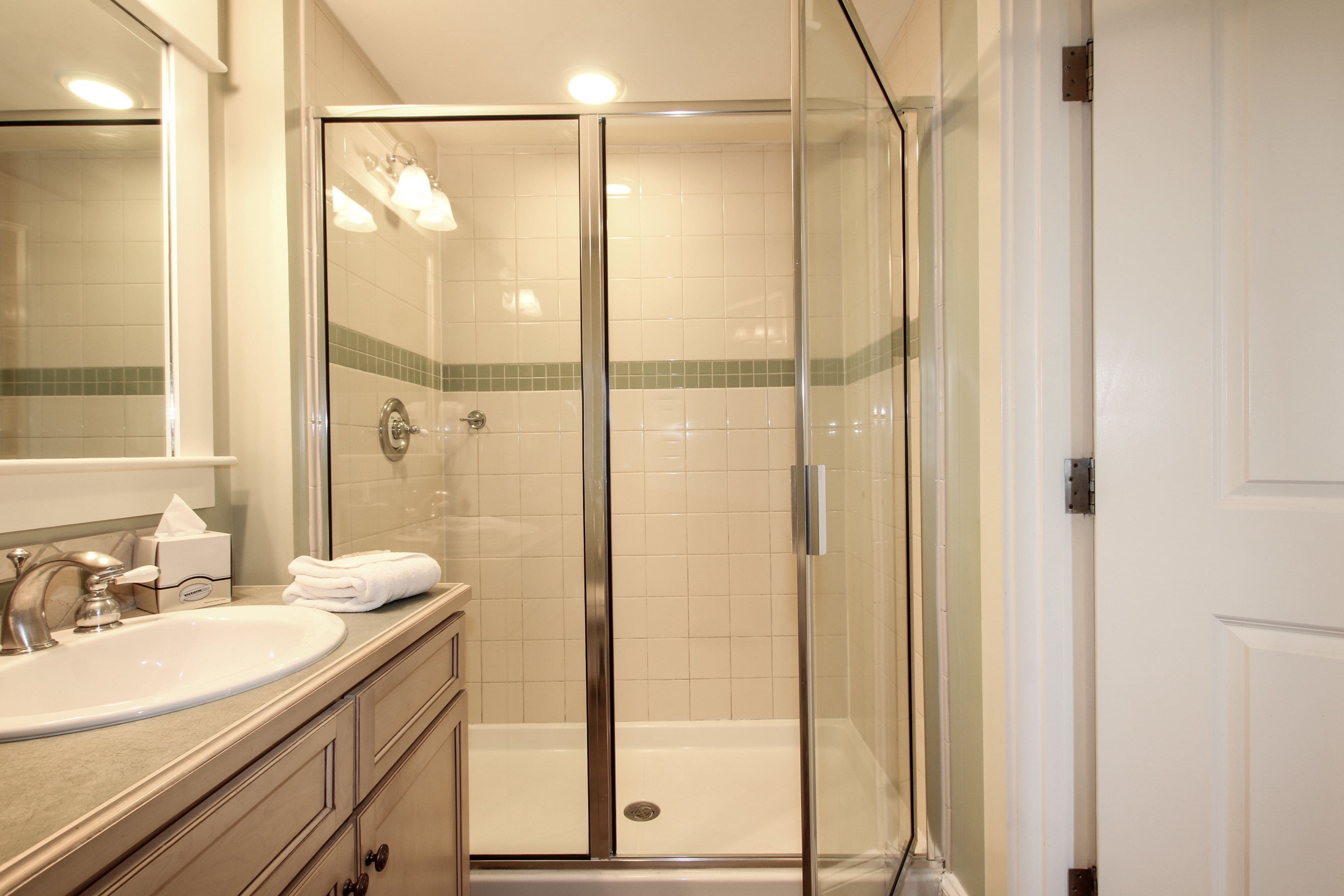 Une salle de bain moderne avec une douche à parois de verre, un lavabo et un miroir.