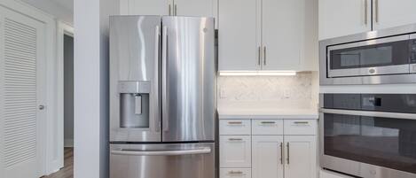 Una cocina moderna con electrodomésticos de acero inoxidable, armarios blancos y salpicadero de baldosas tipo espiga.