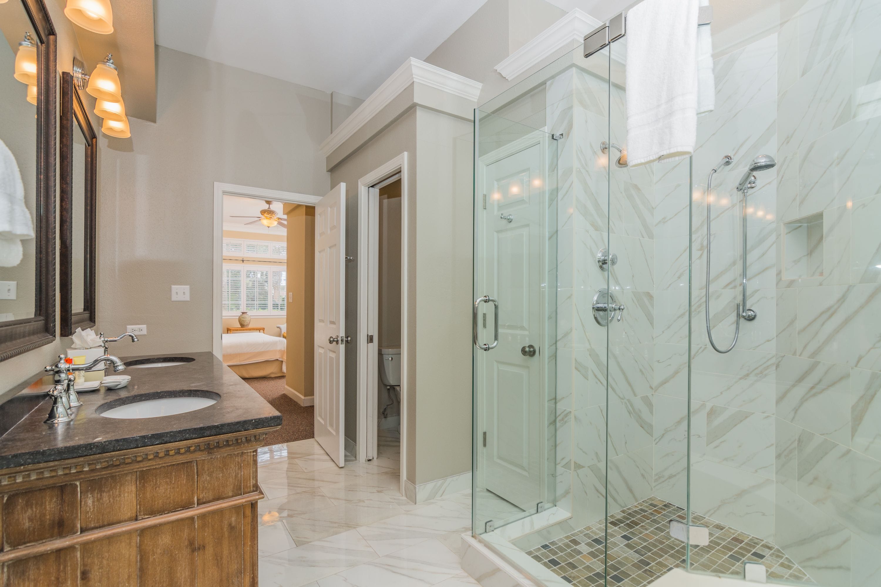 A modern bathroom with a glass-enclosed shower, double sinks, and a vanity with a mirror.