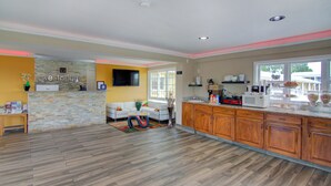 A spacious kitchen with wooden cabinets, a stone accent wall, and a dining area with a sofa and table. - Westbridge Inn and Suites (Clinton)