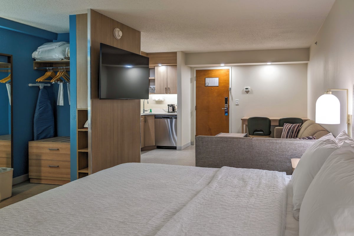 Et hotelværelse med seng, fjernsyn, tekøkken og siddeplads.