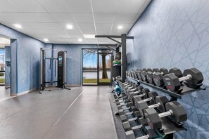 Un gimnasio con equipo de ejercicios, incluyendo mancuernas y una estructura para sentadillas.