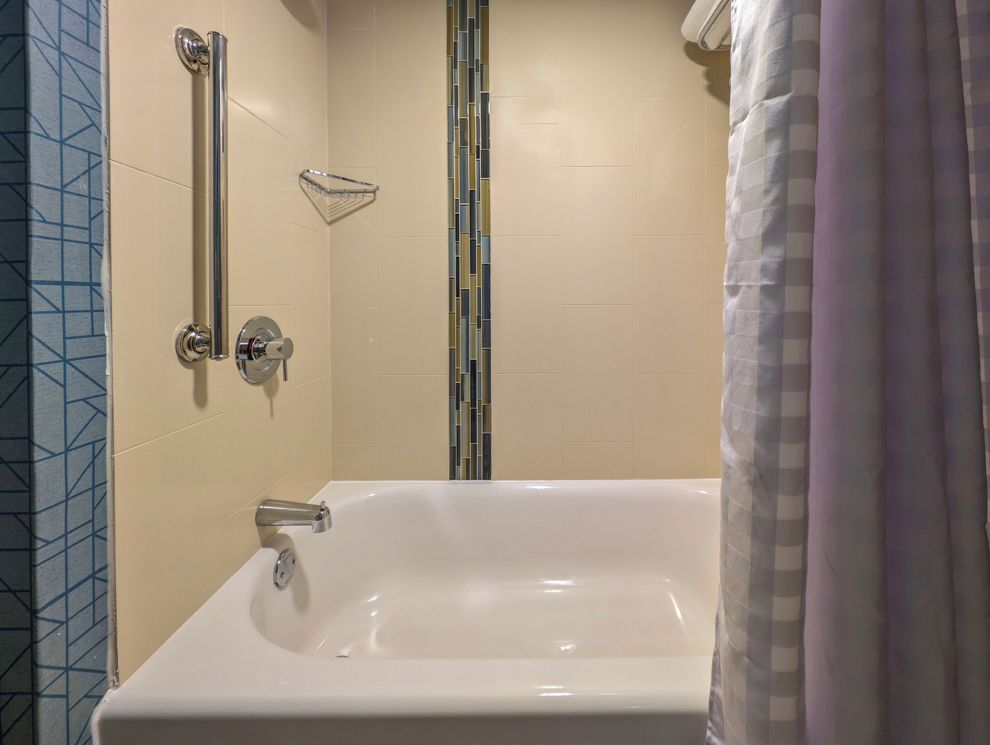 A bathroom with a bathtub, a shower area, and a towel rack.