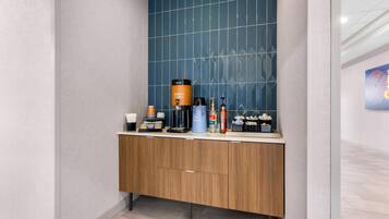 A modern bathroom with a wooden vanity, a coffee maker, and toiletries.