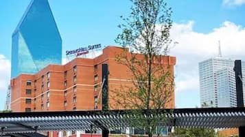 A hotel with a modern glass facade and a brick building in the background.