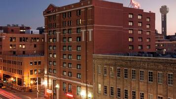 A multi-story hotel with a prominent red brick facade, multiple windows, and a visible neon sign on the rooftop.