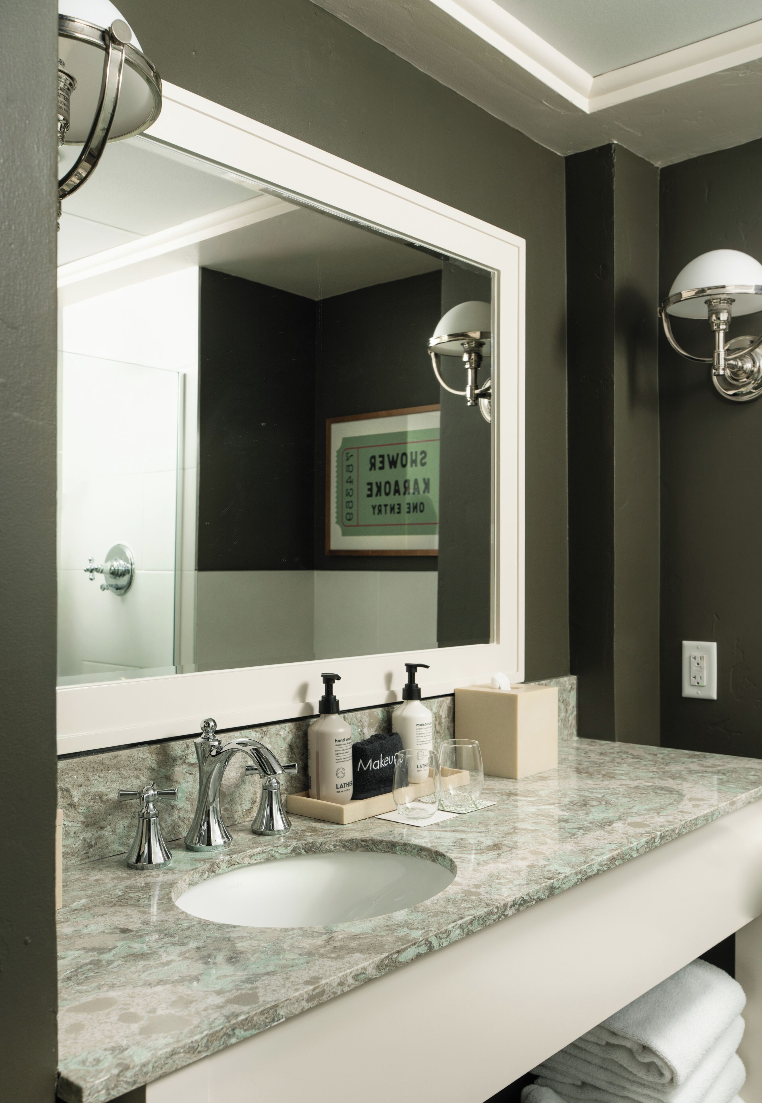A bathroom with a large mirror, a sink, and two wall-mounted lights.