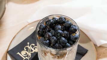 Ein Joghurtglas mit Blaubeeren auf einem Teller, inklusive Löffel.