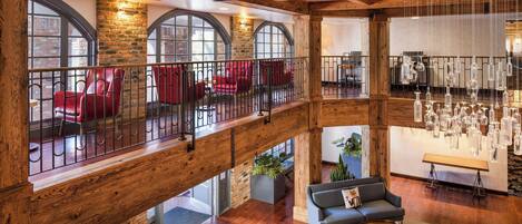 Eine geräumige Lobby mit Holzboden, roten Stühlen, einem grauen Sofa und einer hängenden Leuchte.