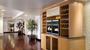 A hotel lobby with a wooden reception desk, glass display cases, and potted plants.