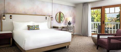 A hotel room with a large bed, a desk, a chair, and a view of the outdoors.