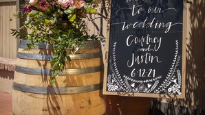 A wooden barrel and a chalkboard sign with wedding details.
