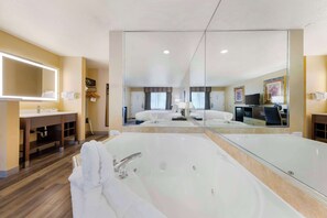 A modern bathroom with a large mirror, a bathtub, a vanity with a sink, and a shower area.