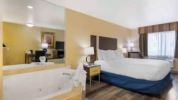 Habitación de hotel con una cama grande, un baño con bañera, un escritorio y una televisión.