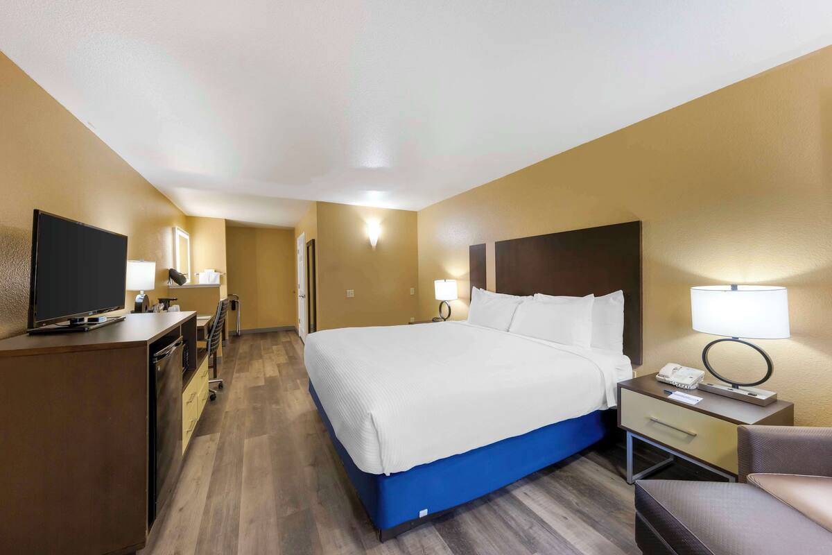 Une chambre d’hôtel avec un grand lit, des tables de chevet, un bureau, une télévision et une chaise.