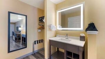 A bathroom with a large mirror, a sink, and a towel rack.