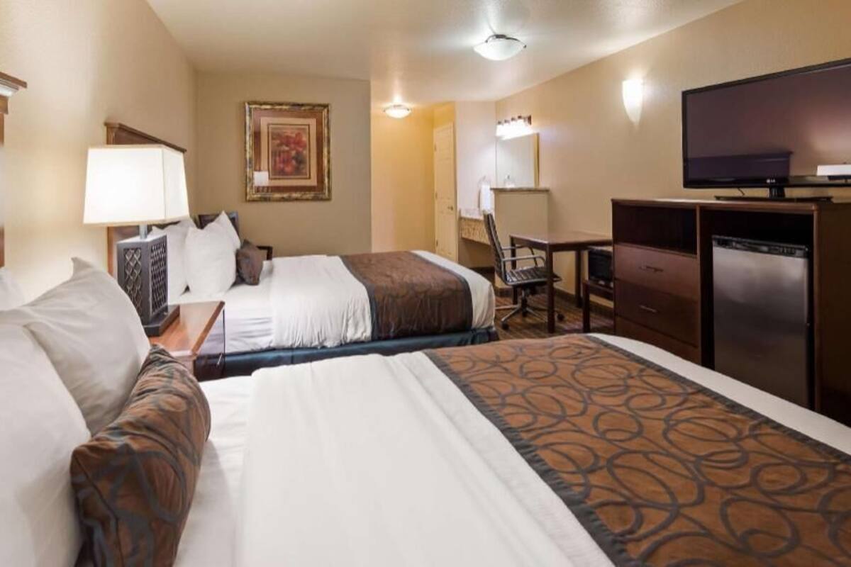 Une chambre d’hôtel avec deux lits, un bureau, une télévision et un réfrigérateur.