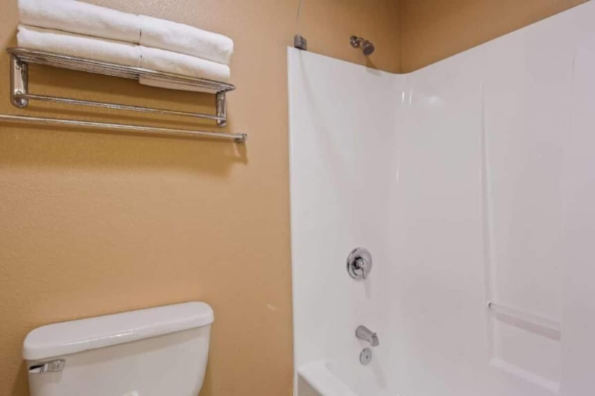 Une salle de bain avec des toilettes, une douche dotée d’une porte blanche et un porte-serviettes avec des serviettes pliées.