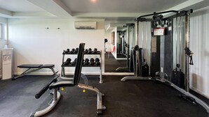 A gym with exercise equipment, a bench, and a rack of dumbbells.