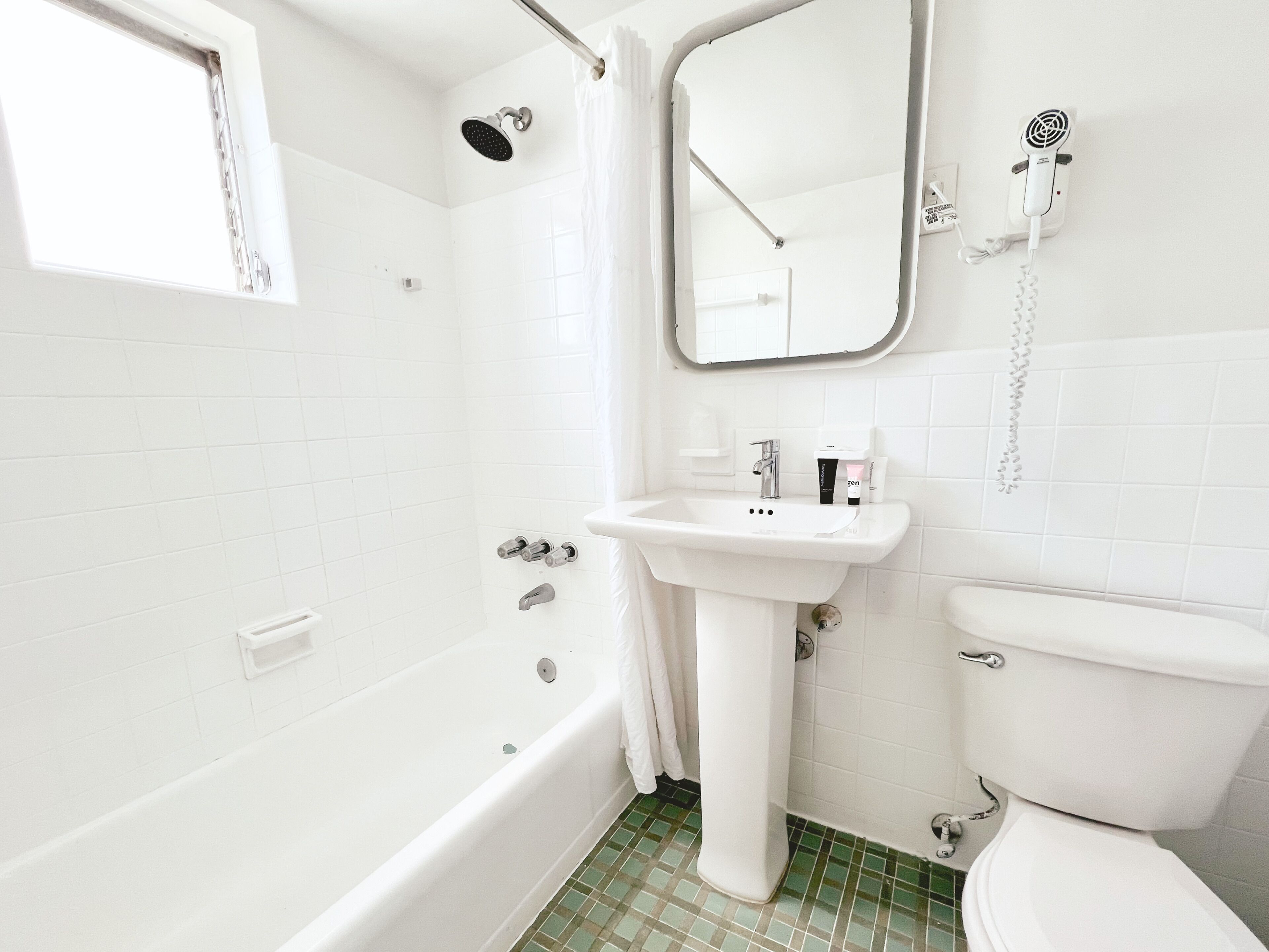 Ein Badezimmer mit Badewanne, Waschbecken, Toilette, Duschkopf und Fön.