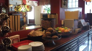 A breakfast bar with various food items, a clock, and a mirror. - Inn at St John Portland In-Town (Portland)