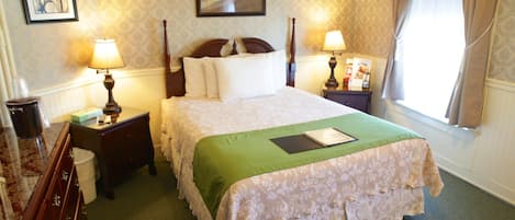 A neatly arranged hotel room with a large bed, two bedside tables with lamps, a dresser, and a window with curtains.