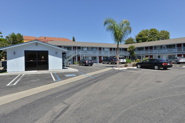 A motel with a small attached garage, a covered parking area, and a two-story building with a red-tiled roof.