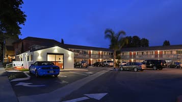 Ein Hotel mit modernem Design, das einen Parkplatz mit mehreren Autos und ein Hotel-Schild zeigt.