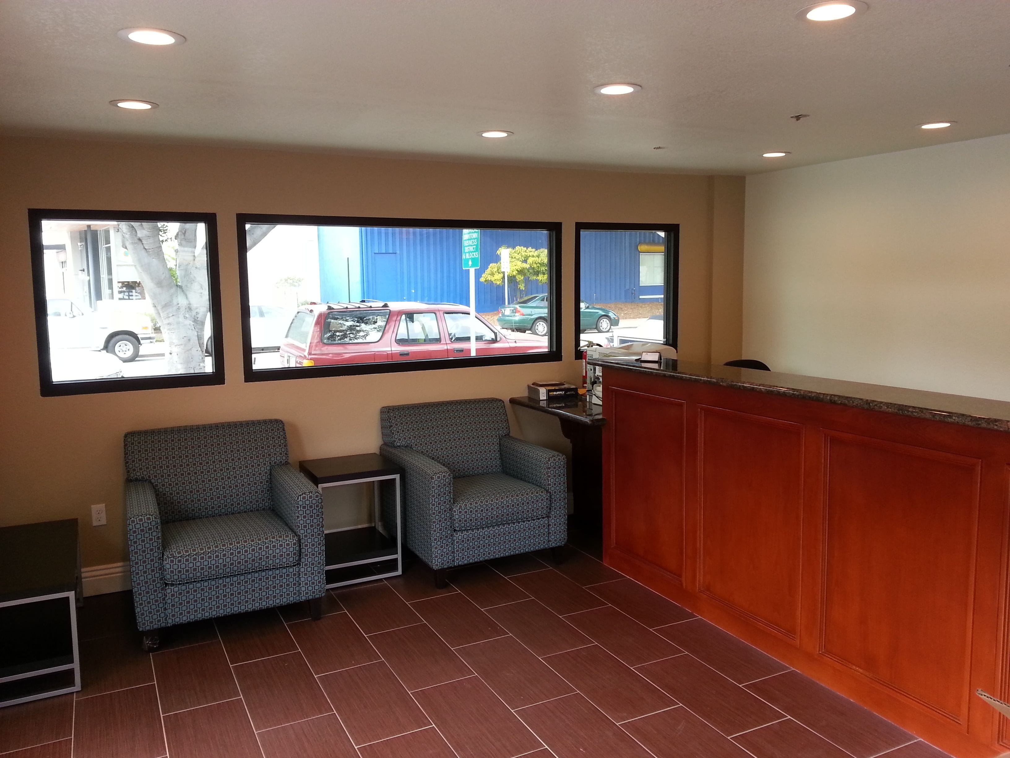 A reception area with a wooden counter, two patterned armchairs, and a small table.