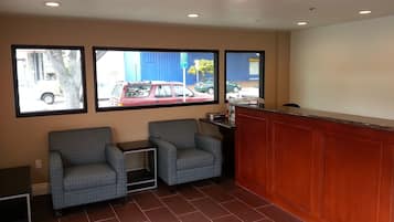 A reception area with a wooden counter, two patterned armchairs, and a small table.