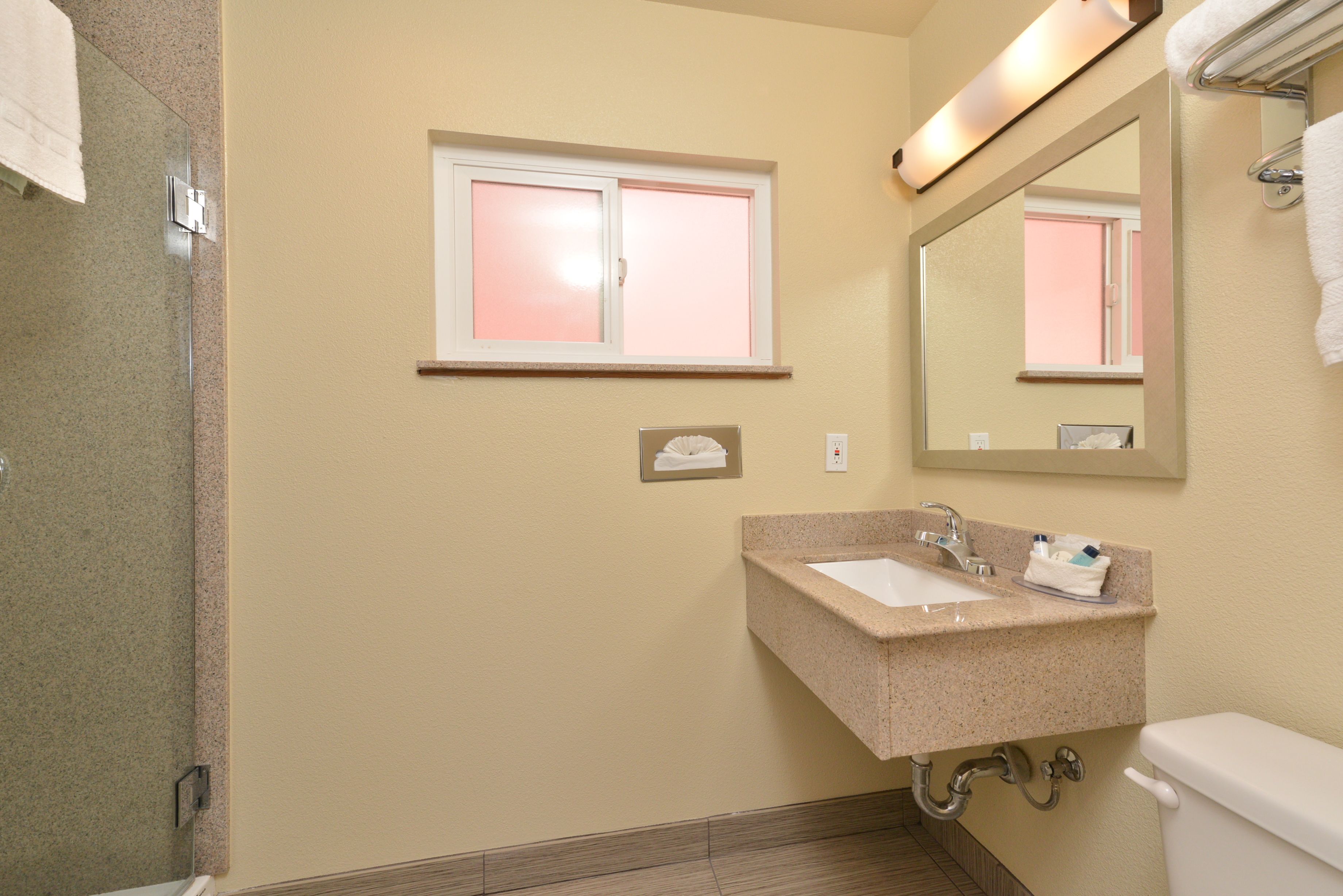 A bathroom with a sink, mirror, and window.