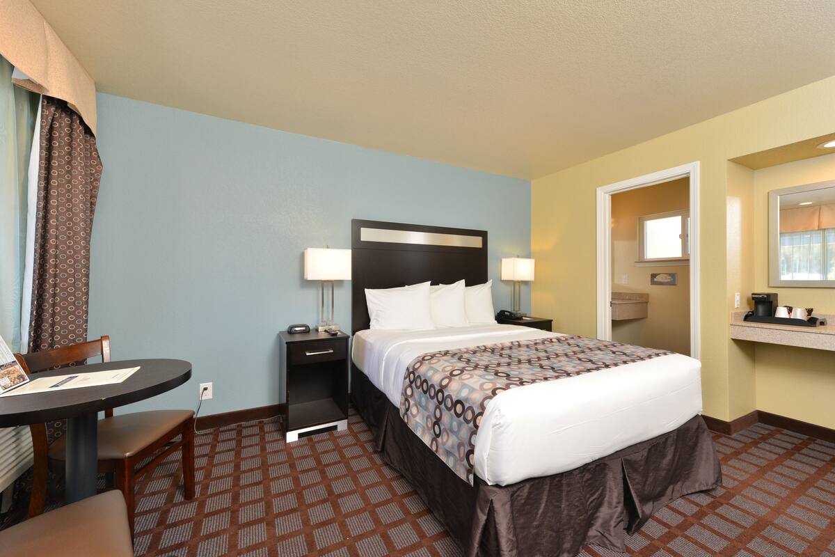 Ein Hotelzimmer mit Bett, Nachttischen, Schreibtisch und Stuhl.
