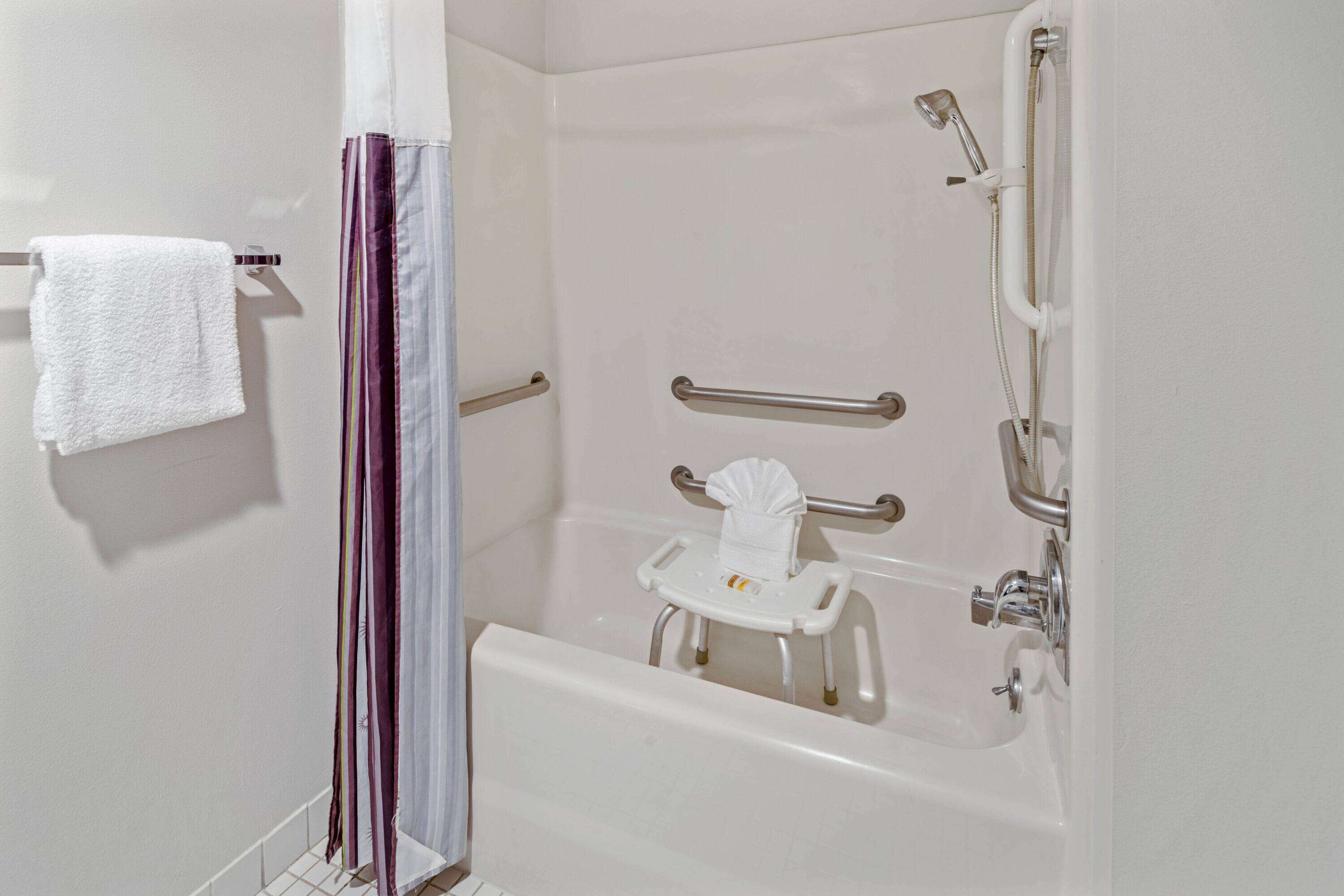 Un baño con bañera, ducha y barras de apoyo.