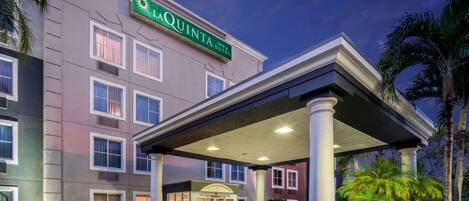 L’entrée d’un hôtel, avec un passage couvert, des palmiers et une enseigne indiquant « LAQUINTA INN & SUITES ».