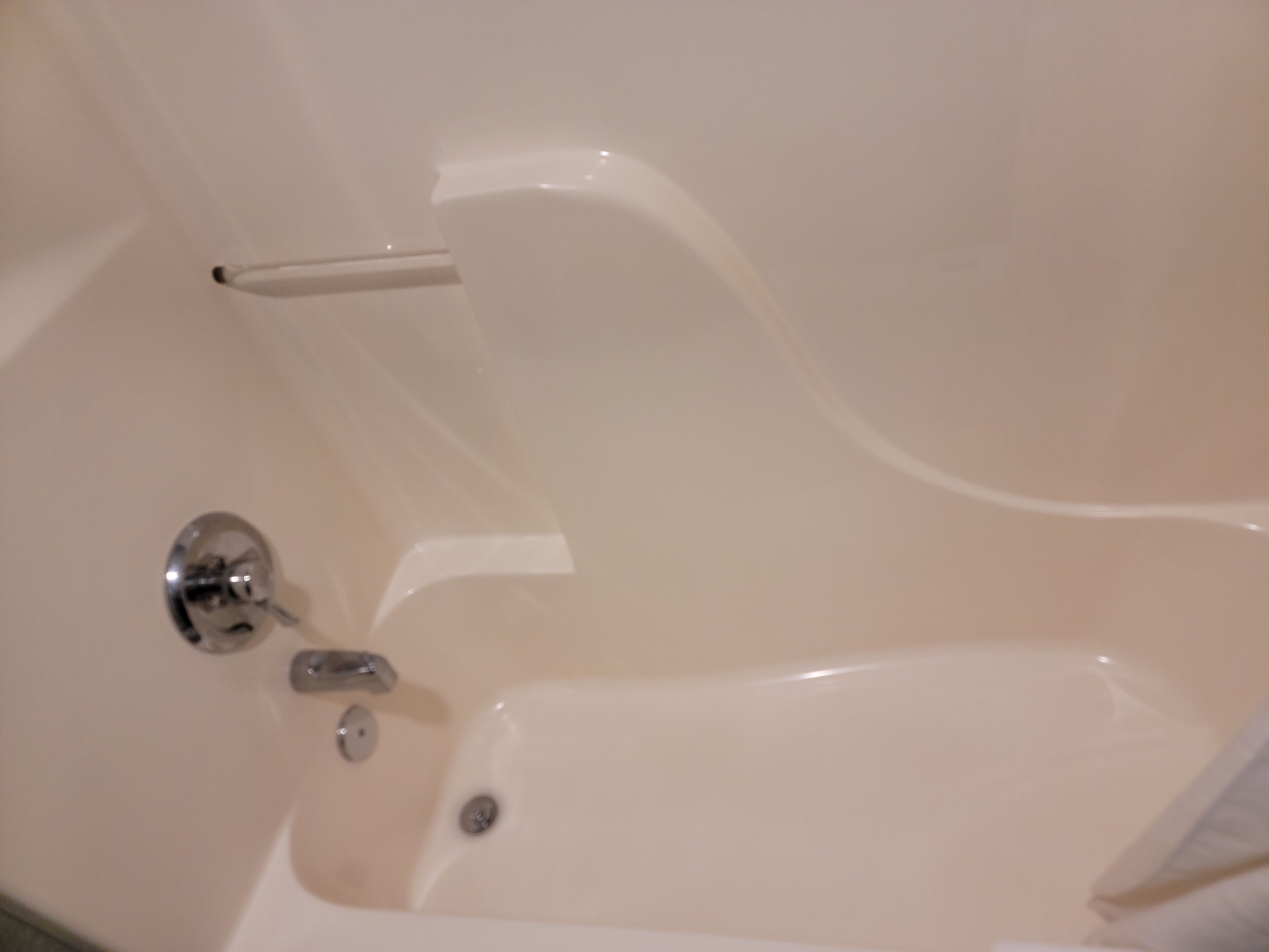 A bathtub with a chrome faucet and a single chrome knob.